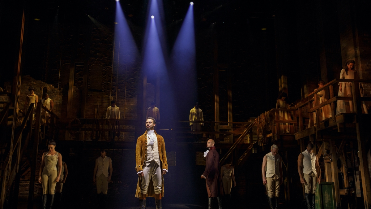 The cast of the Broadway musical Hamilton stands onstage.