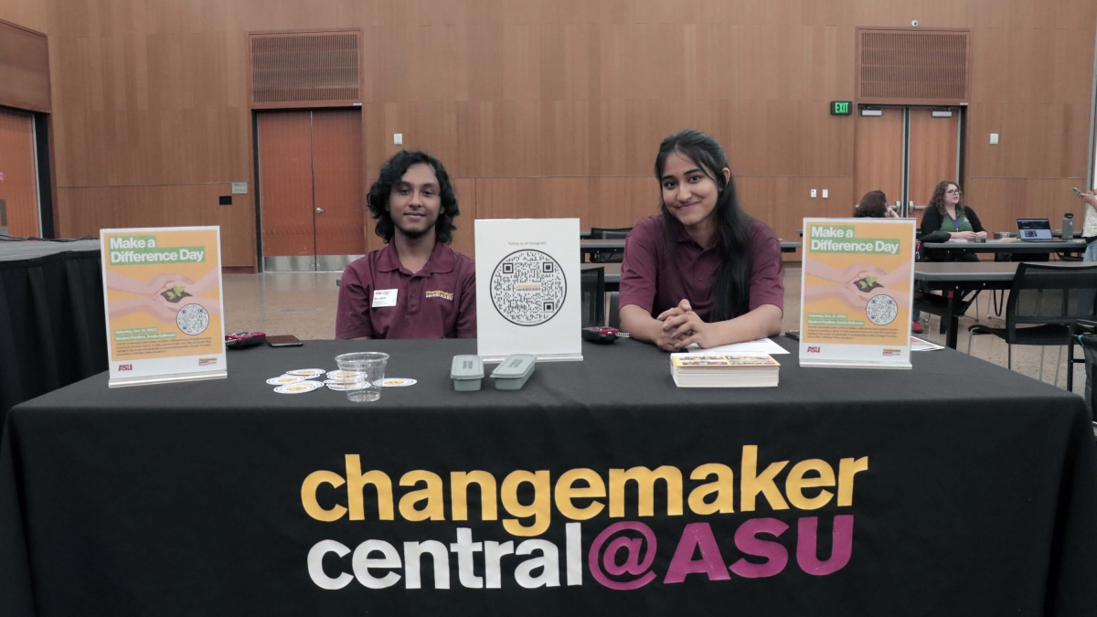 Two students seated at a table with a sign that reads "Changemaker Central @ASU"
