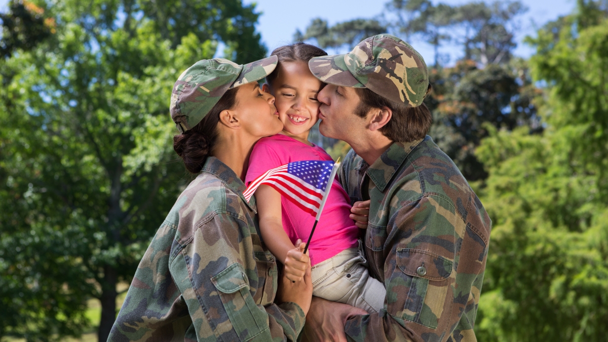 Picture of couple in military clothes holding and kissing their young child.