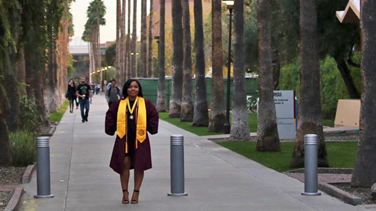 ASU student in cap and gown on Palm Walk