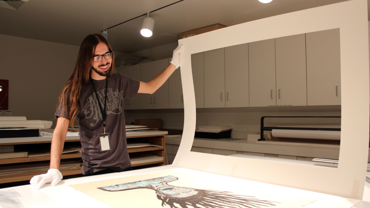 ASU student Dillon Vaughn looking at a large art print