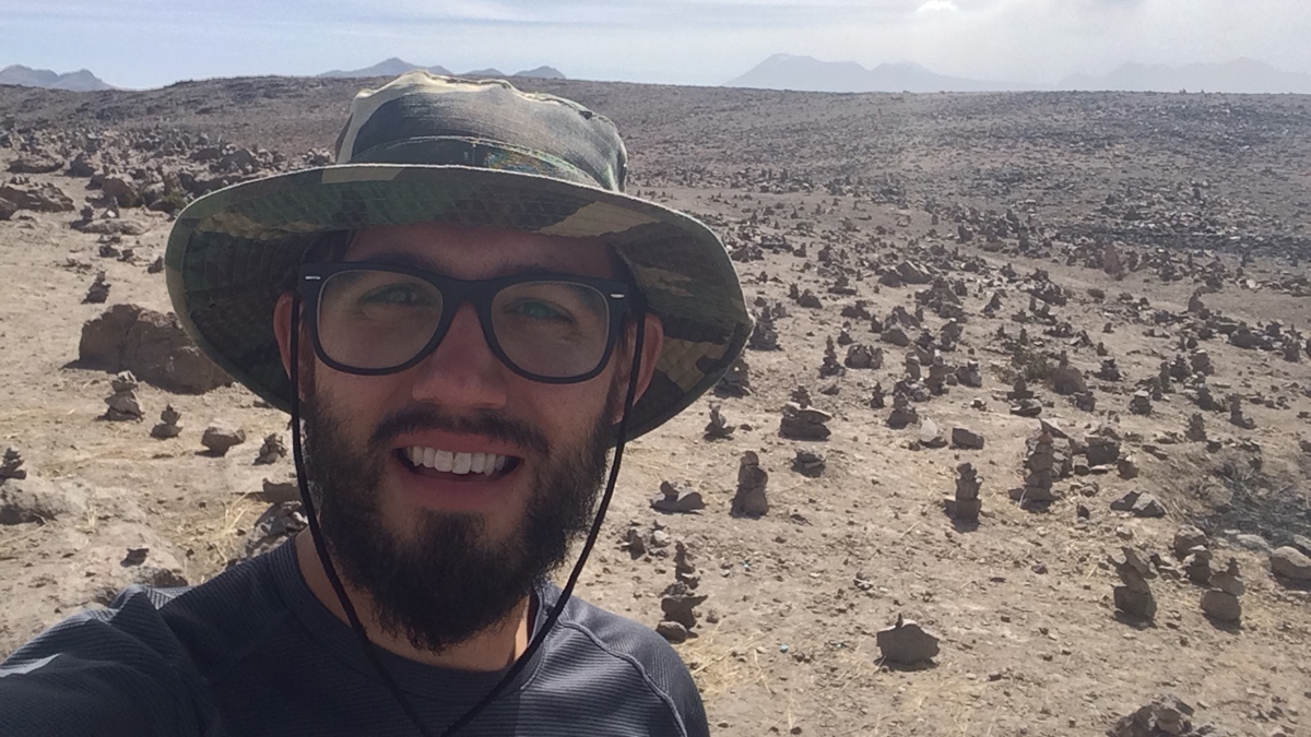 ASU graduating PhD Donald Glaser posing for a selfie in a desert landscape.