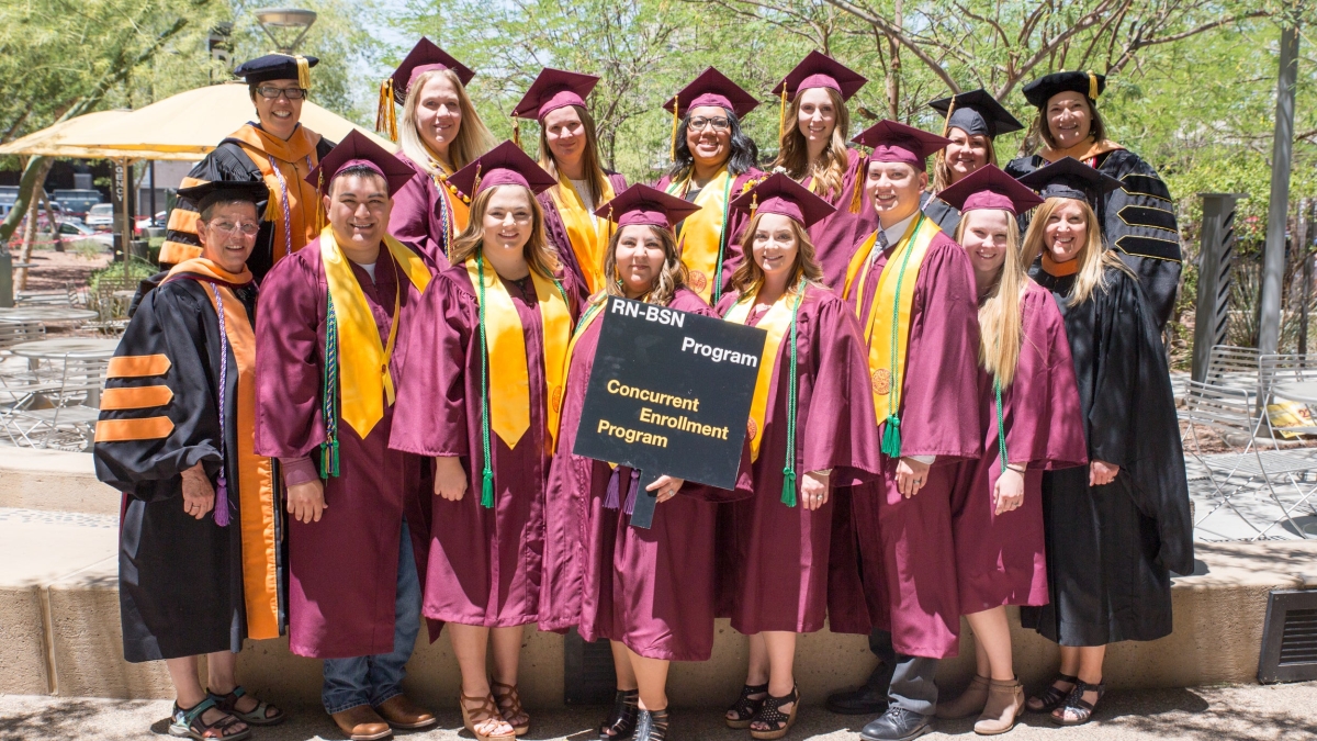 Graduates pose in their maroon caps and gowns on graduation day at the ASU Edson College of Nursing and Health Innovation building