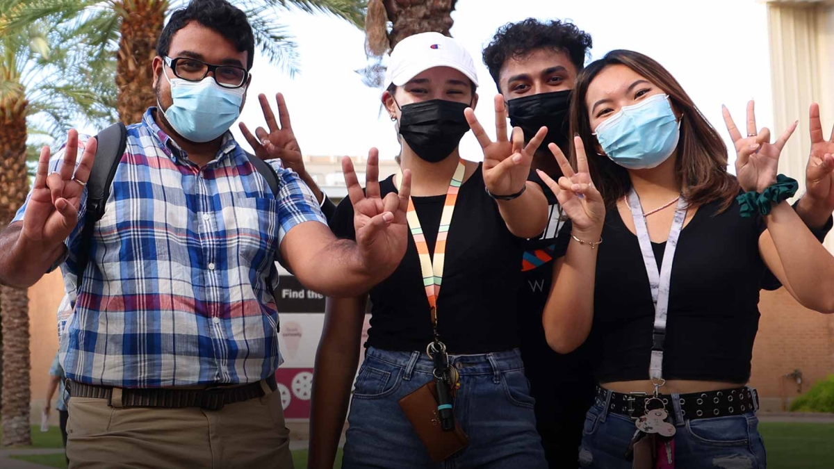 Students wearing masks hold up pitchfork gestures