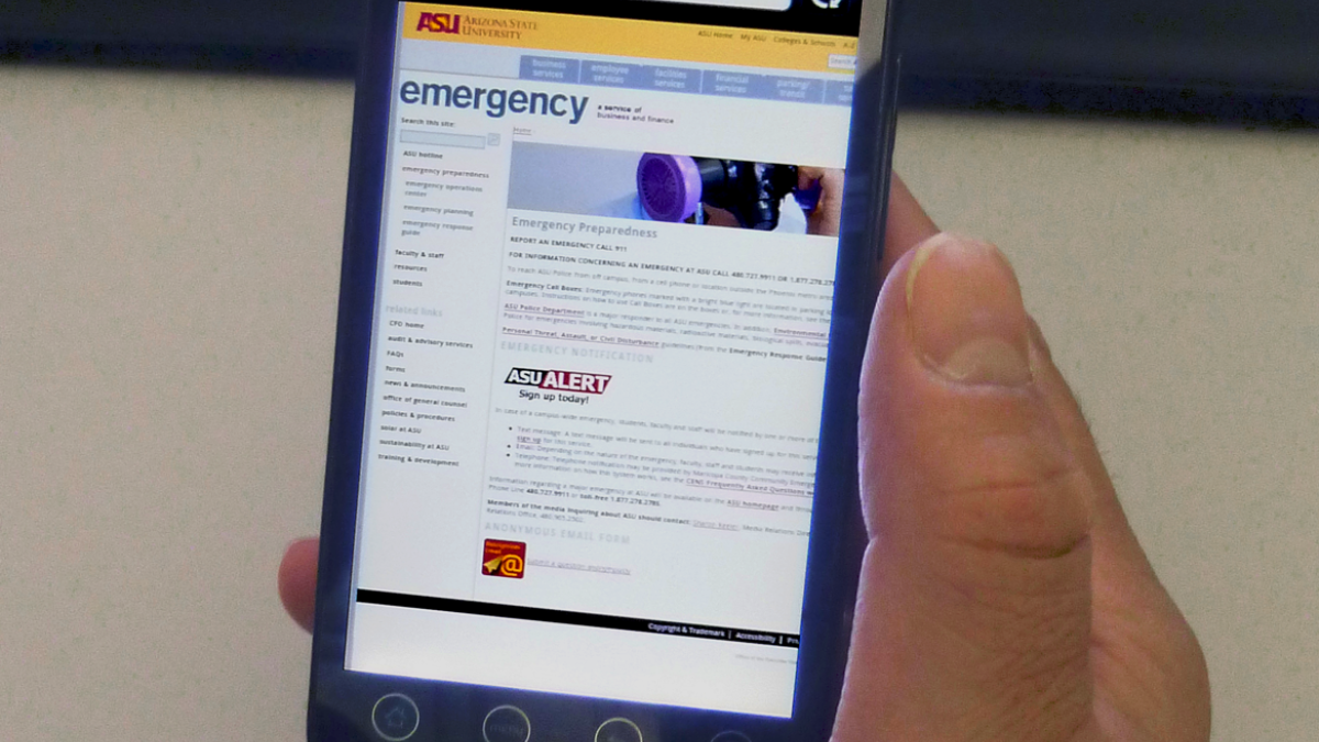 A person is holding a smart phone with the web browser on the ASU emergecny page