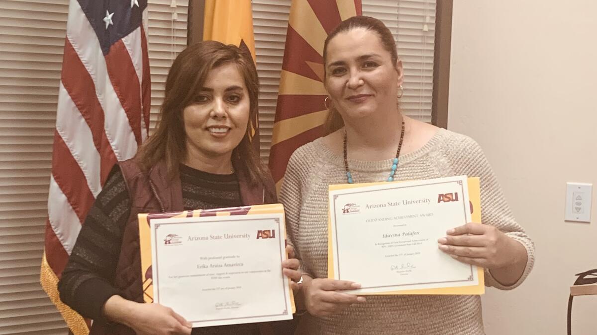 Two women holding up certificates