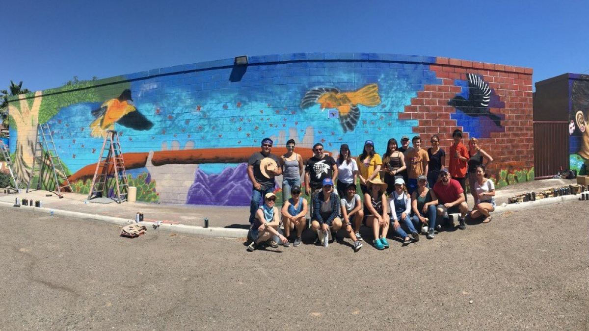 Photo of Facing Immigration II class in front of their mural they helped paint with Hugo Medina