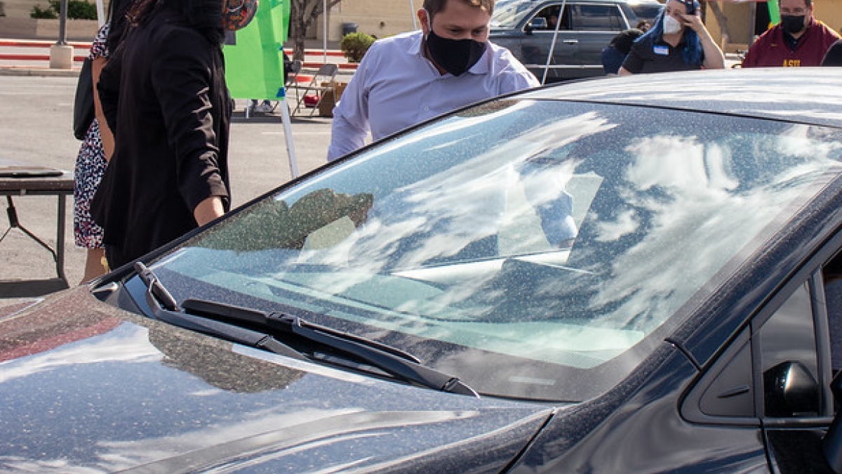 Rep. Ruben Gallego in a mask talking to a passenger in a car 