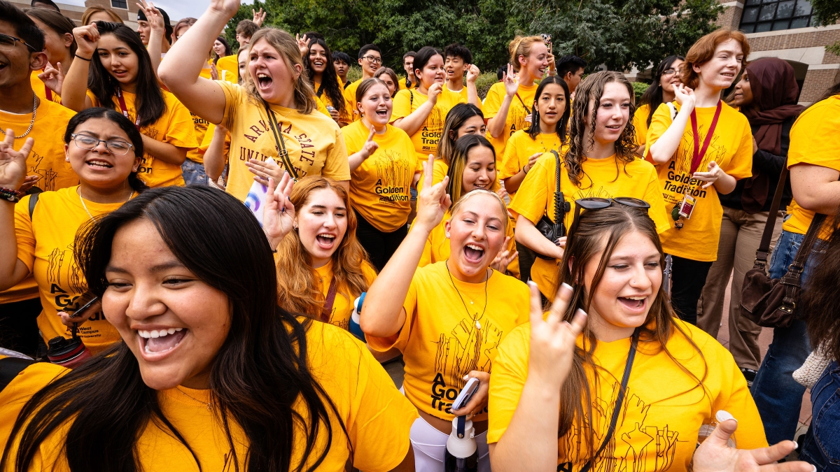 Group of students bunched together in gold t-shirts singing