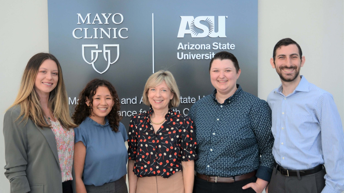 Group of people pose for a photo in front of a sign with Mayo Clinic and Arizona State University logos.