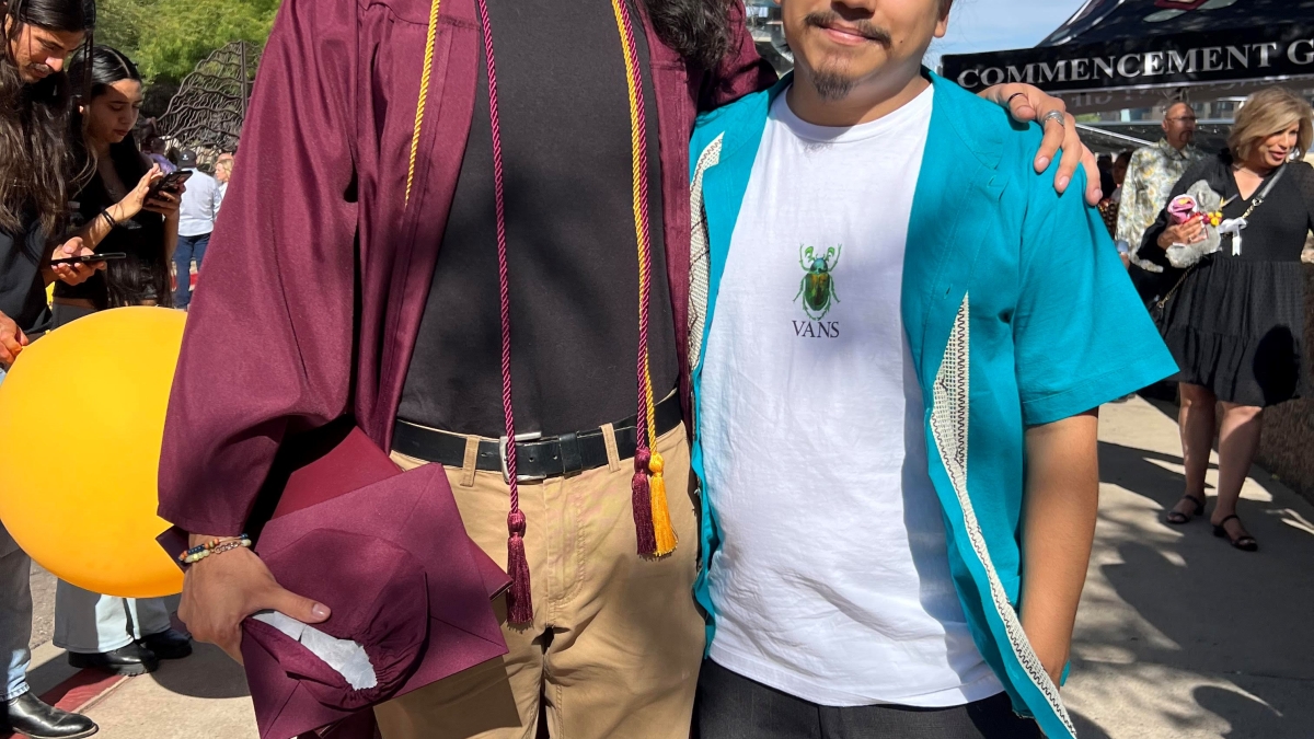 ASU grad George Ramos (left) wears his graduation regalia while standing next to current ASU student Jesus Ledezma.