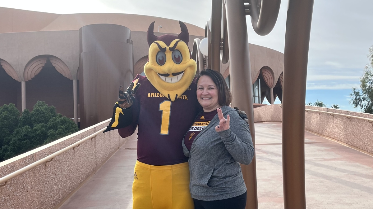 Gina Bounds, a brunette woman with a bob haircut wearing a gray zip hoodie, stands with Sparky. 