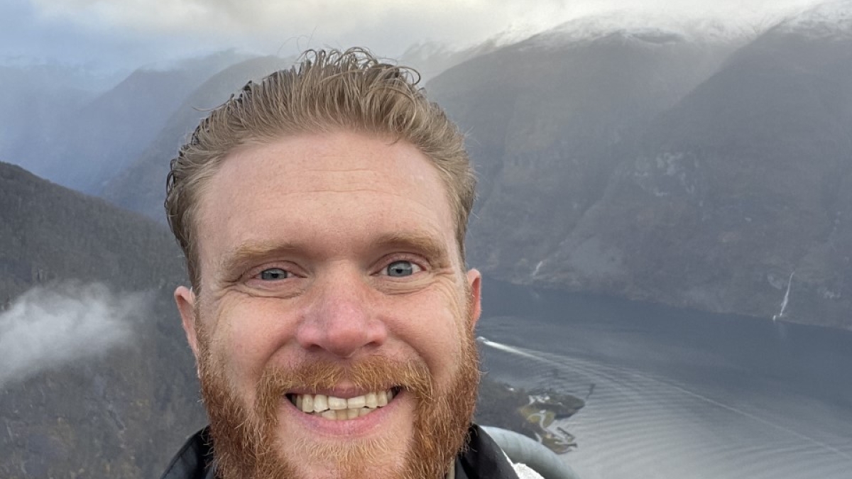Nick Heier smiling with mountains and water in the background