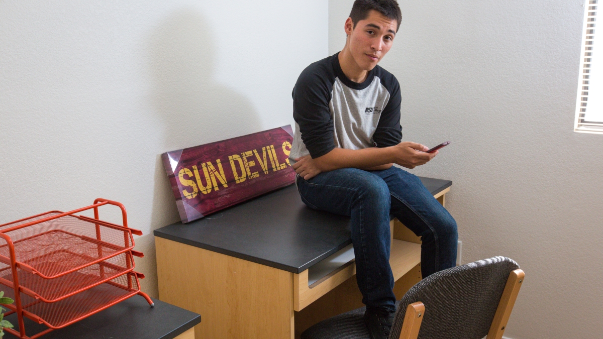 ASU student sitting on his dorm room desk