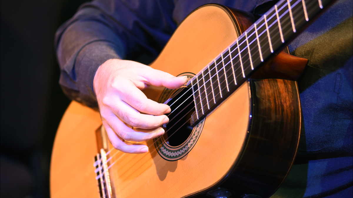 Close-up of a person's hand strumming a guitar.