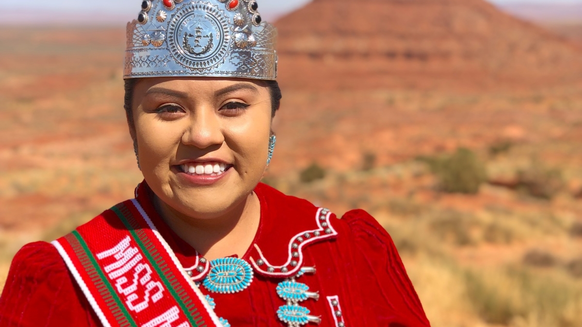 ASU alumna Shaandiin Parrish wearing a crown standing in front of a desert backdrop
