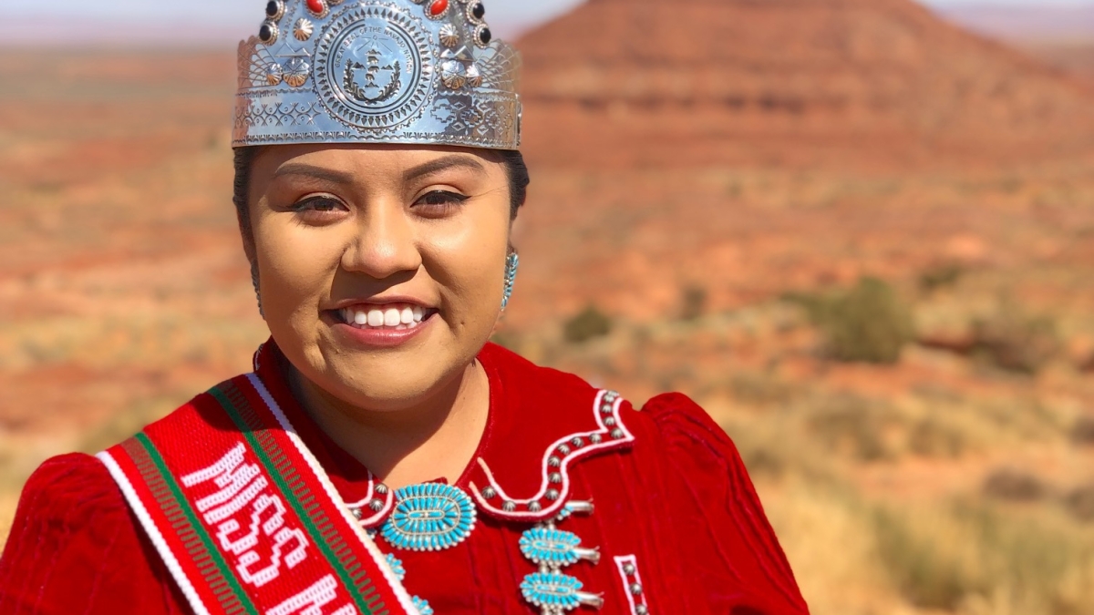 ASU alumna Shaandiin Parrish wearing a crown standing in front of a desert backdrop