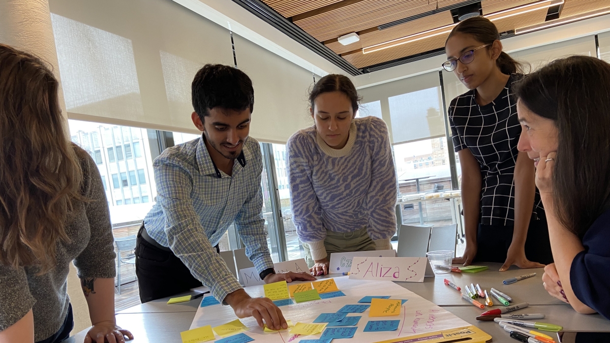 Students leaning over a table with a poster full of sticky notes.