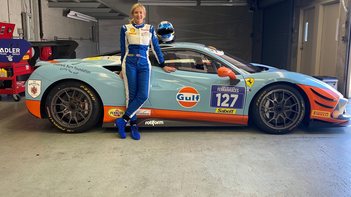 woman posing in front of race car