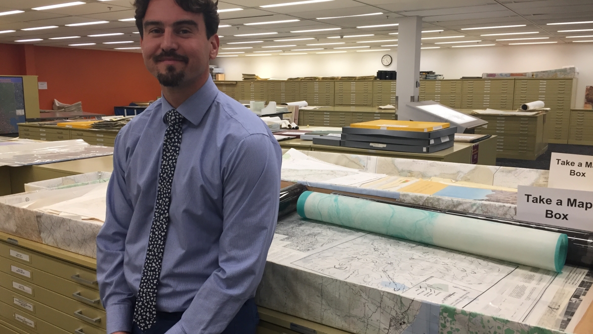 director of Map and Geospatial Hub standing in front of old maps