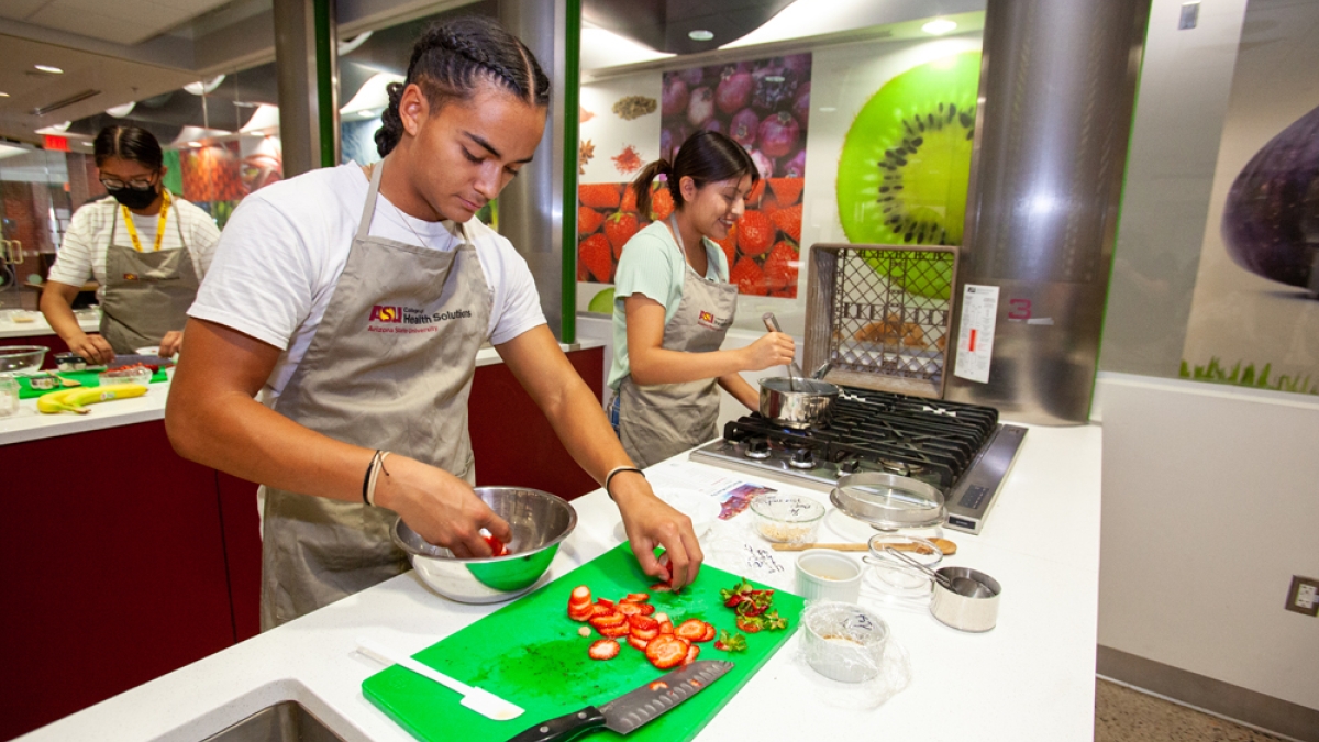 American Indian high school students chopping vegetables on cutting boards in a prep kitchen classroom.