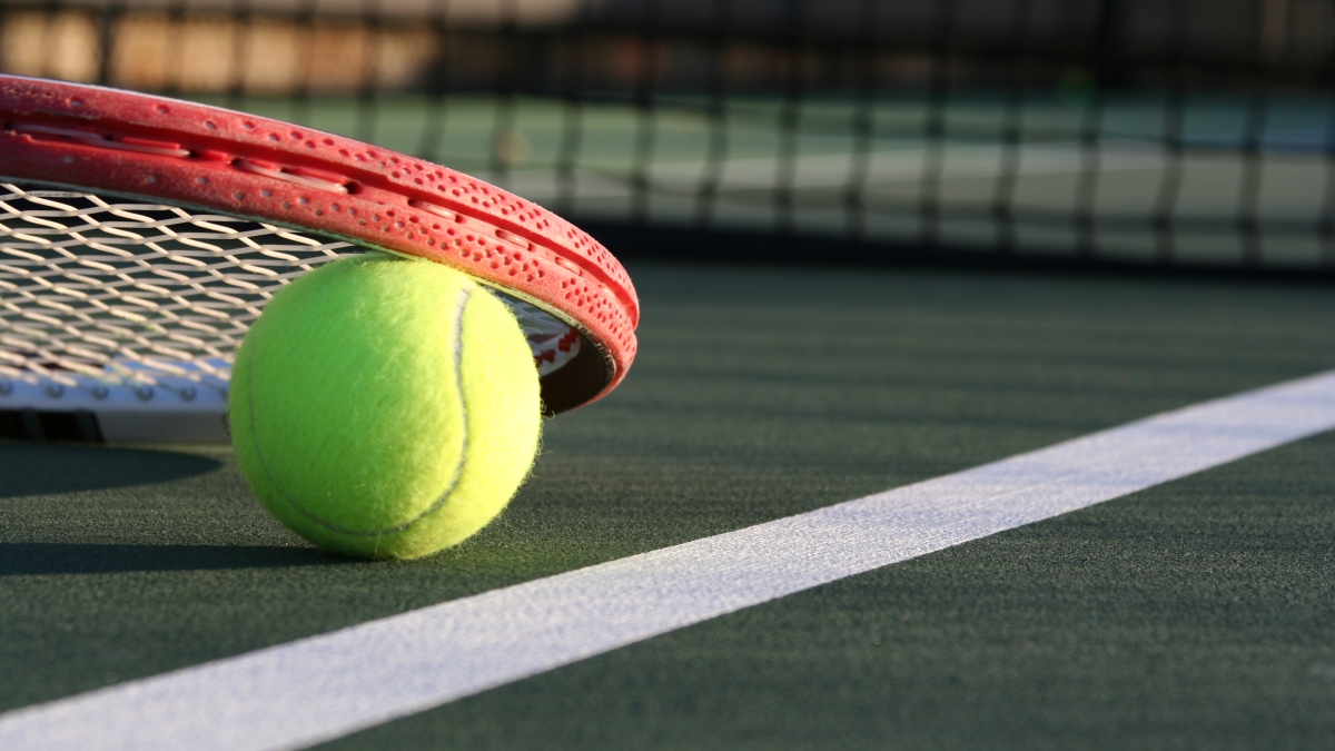 Close-up of a tennis ball and racket on a court.