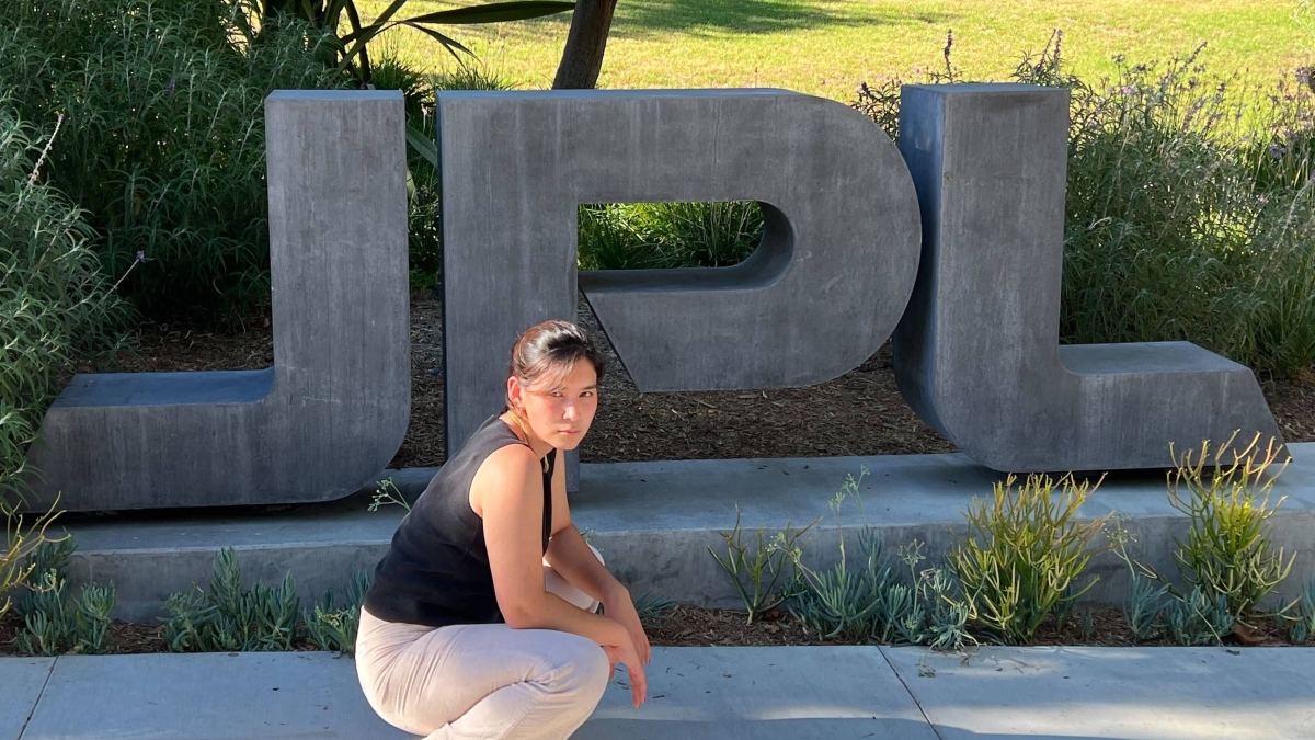 A woman poses in front of the JPL sign