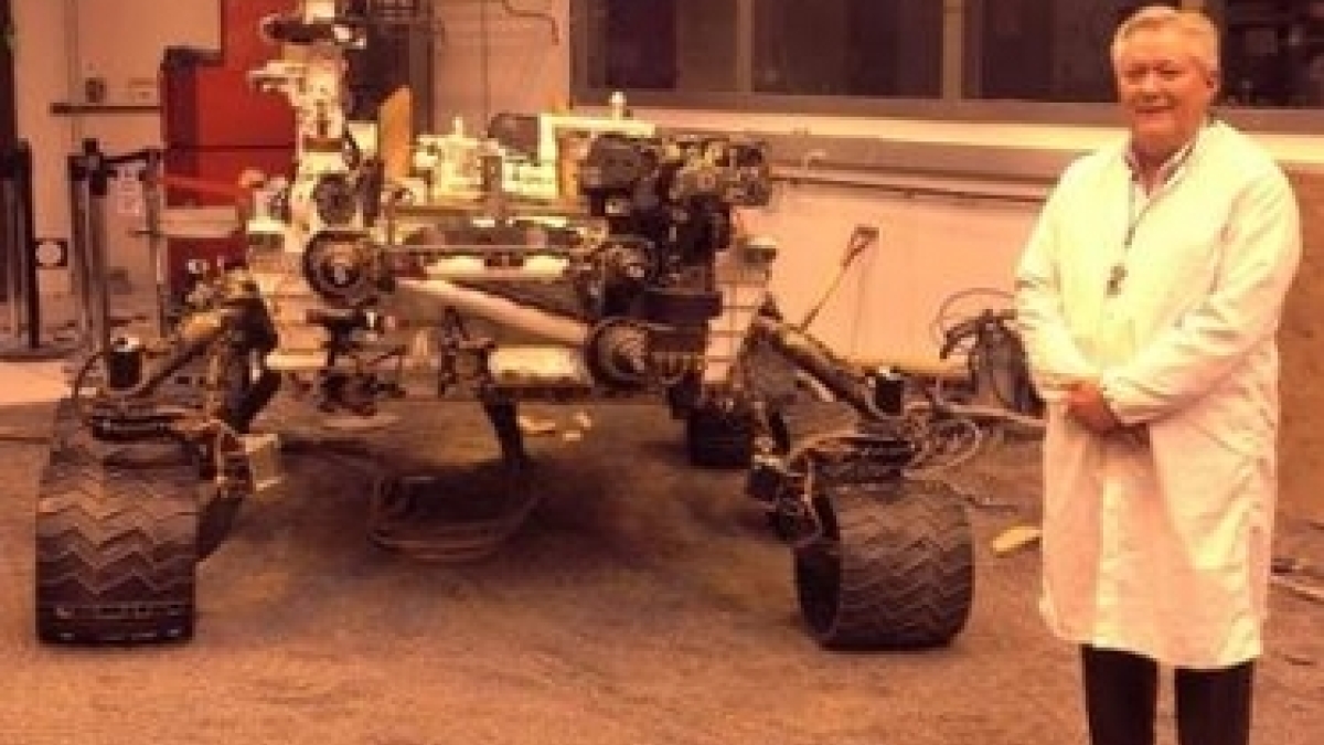 man standing in front of Mars rover replica