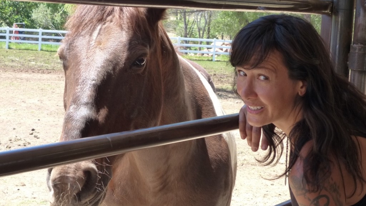 ASU School of Social Work Associate Professor Joanne Cacciatore smiles while posing with a horse