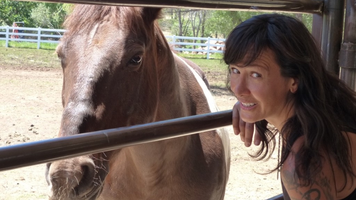 ASU School of Social Work Associate Professor Joanne Cacciatore smiles while posing with a horse