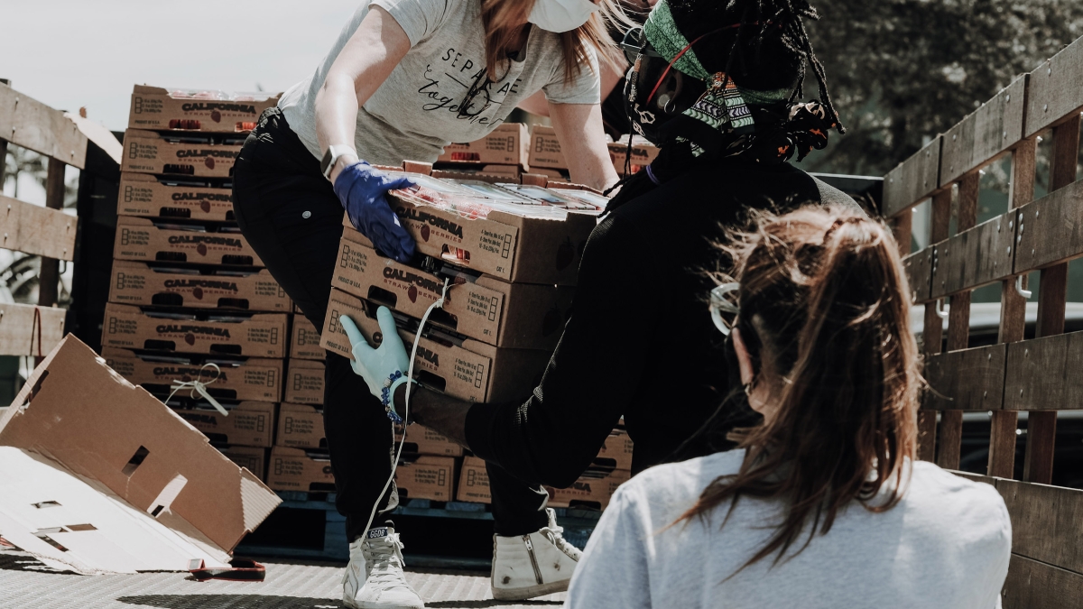 woman wearing a mask, unloading food from a truck
