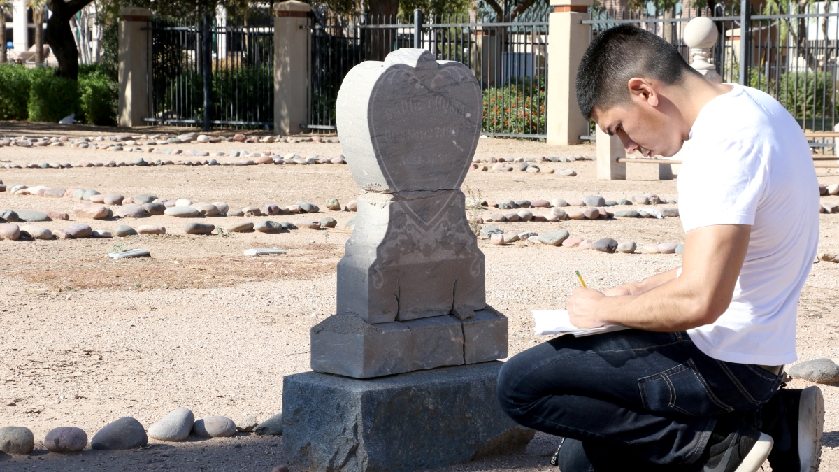 ASU's Juan Carrola takes notes at grave as part of CISA history course