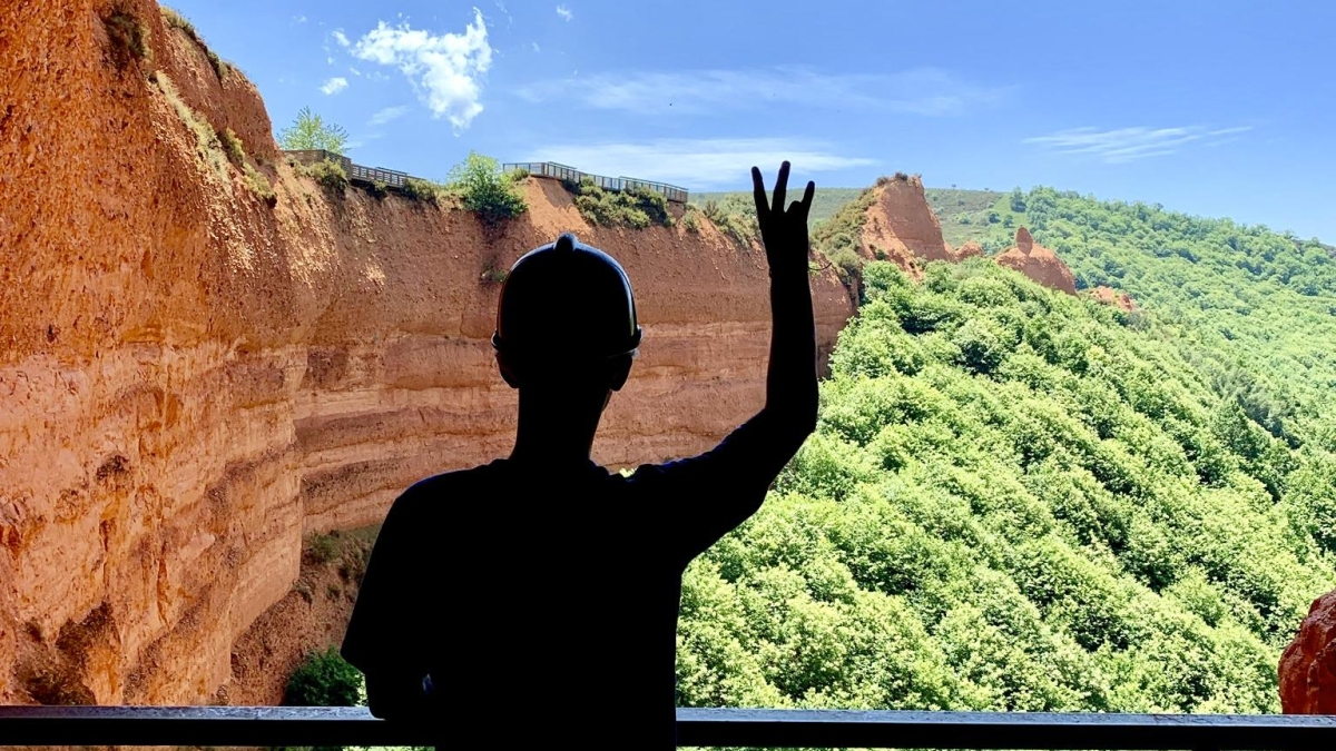 A silhouette of an ASU student holding up a pitchfork overseeing a landing with a forest below in Spain
