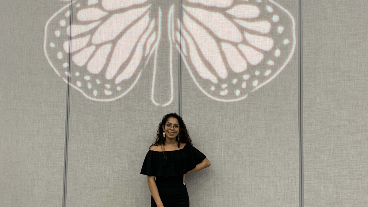 Karina Dominguez stands in front of a butterfly projection