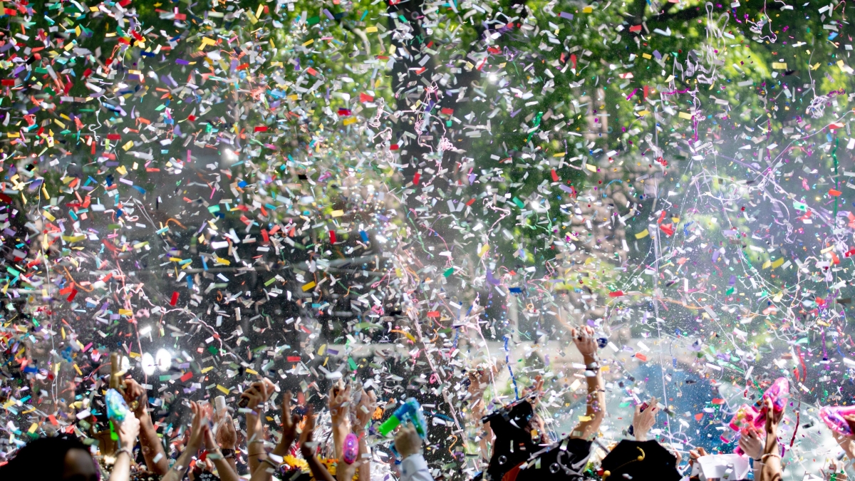 College graduates celebrate as confetti swirls.