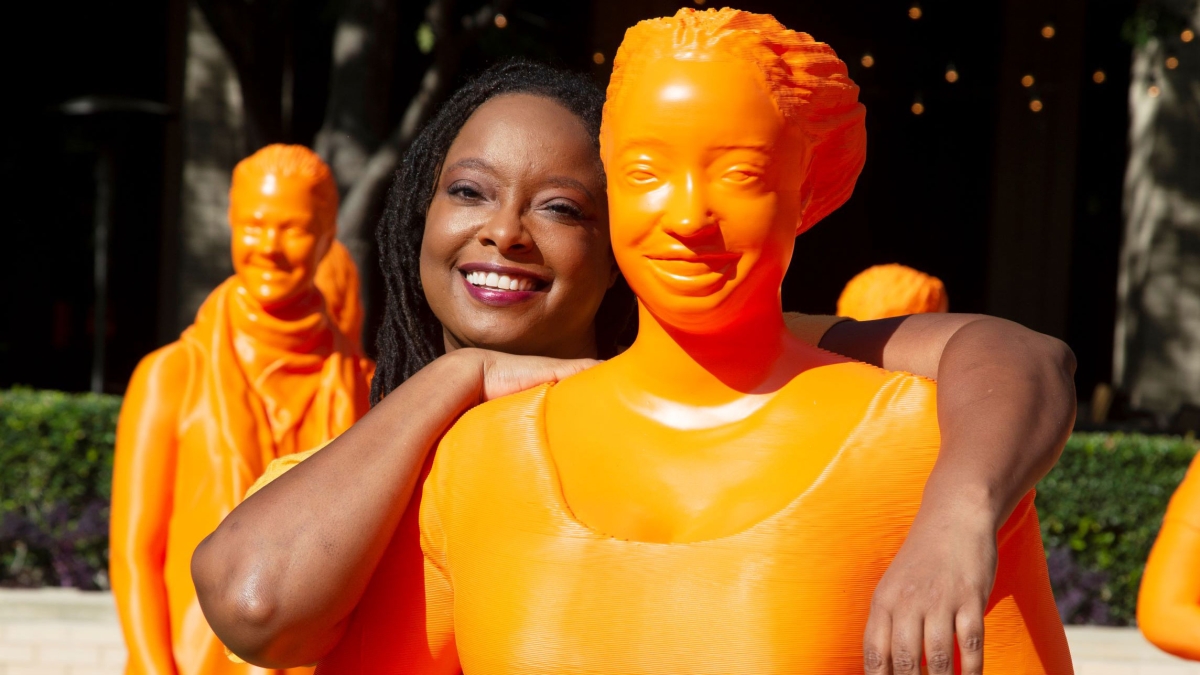 ASU Associate Professor Lelelia Jenkins smiles as she poses with an orange statue of herself.