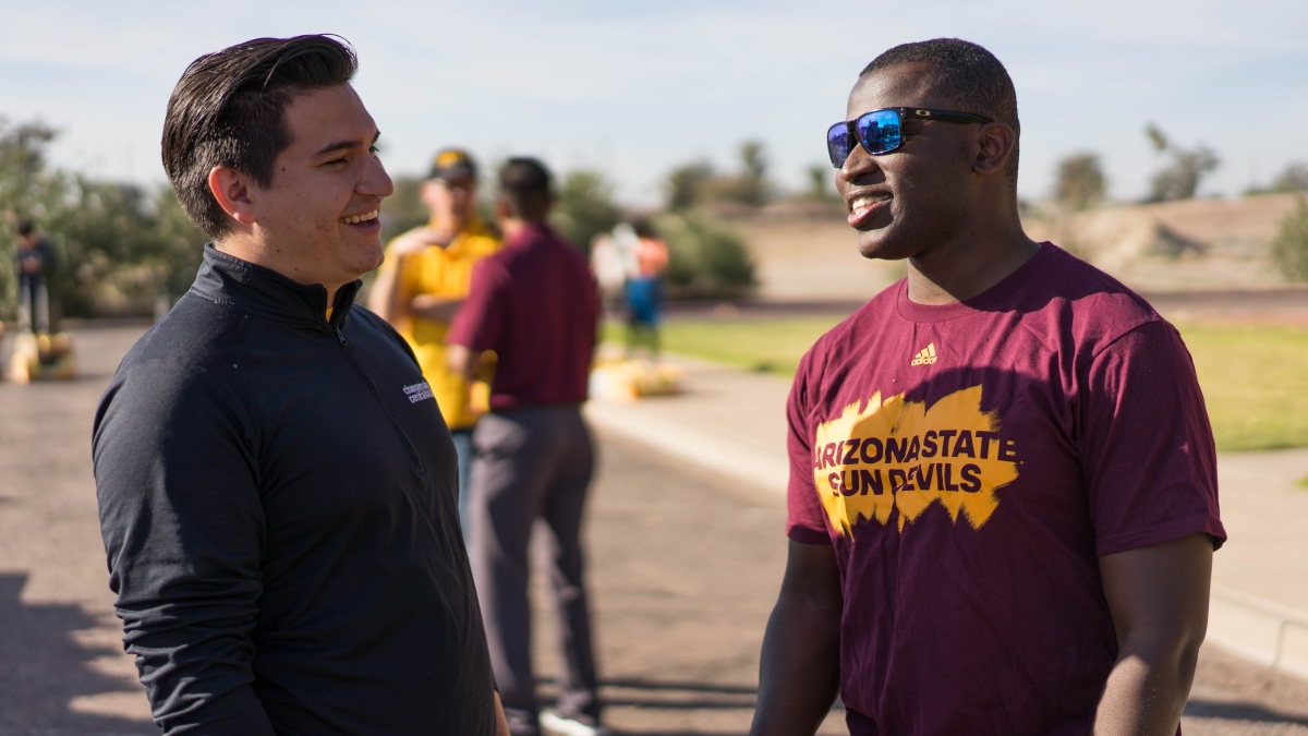ASU students Leirbag Fajardo and Aki Olambiwonnu share a laugh while volunteering at the Borderlands Produce On Wheels With Out Waste event at the ASU Polytechnic campus
