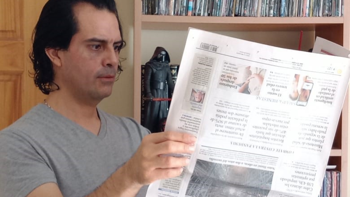Image of Luis Benavides reading an upside down newspaper.