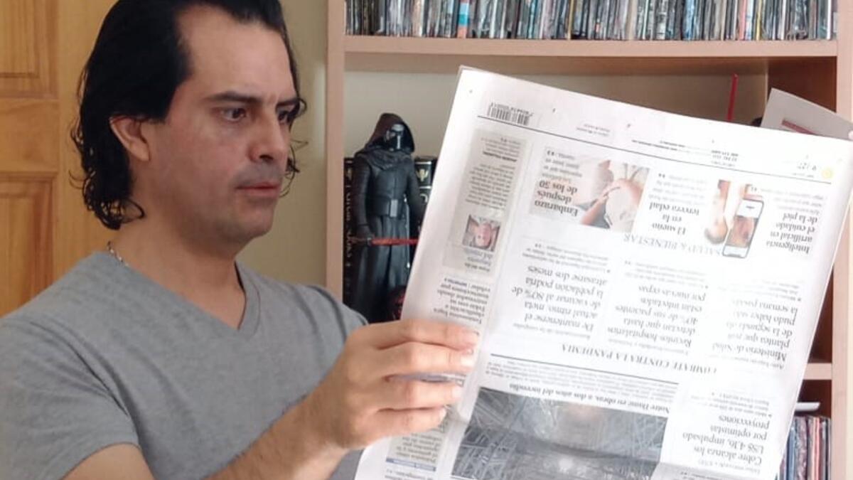 Image of Luis Benavides reading an upside down newspaper.