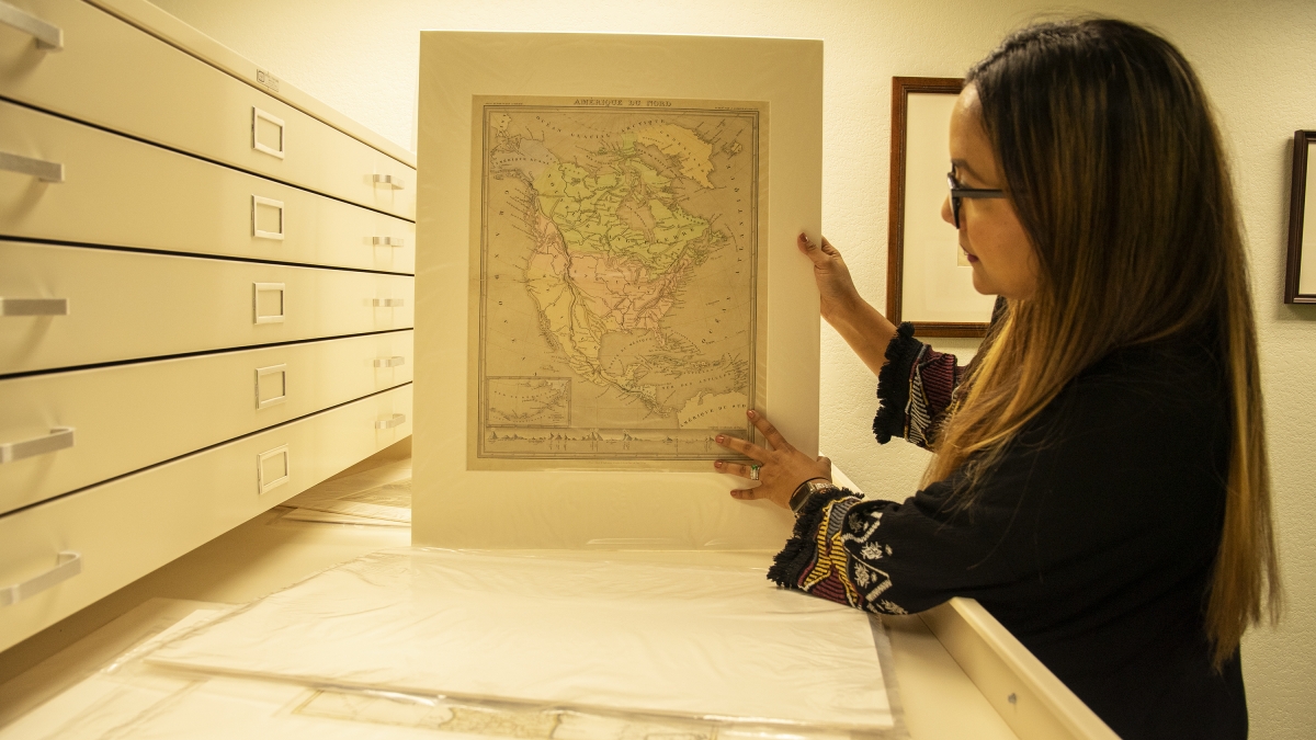 Program for Transborder Communities Program Manager Mara Lopez shows one of the historic maps that will be displayed in the newly-curated exhibit at the School of Transborder Studies.