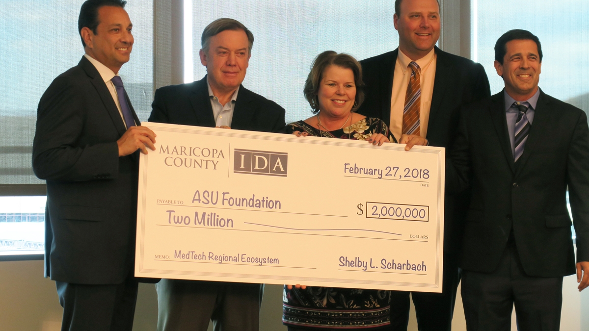 group of 5 people holding giant check