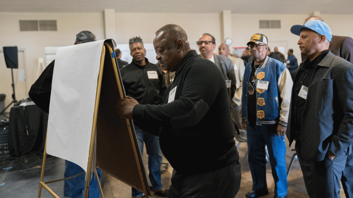 Men draw on an easel at a conference