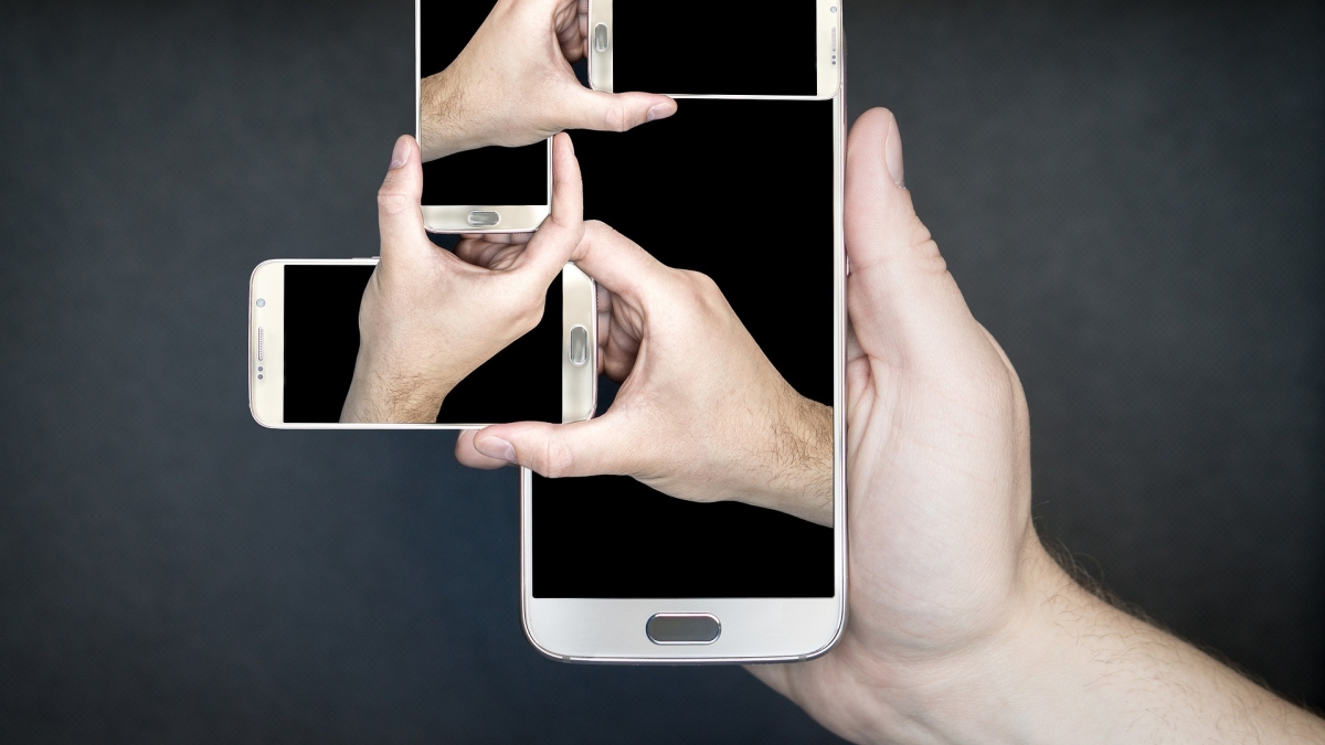Abstract photo illustration of several hands holding several smartphones.