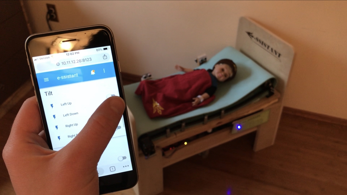 someone holding a smartphone with a doll laying on a bed in background