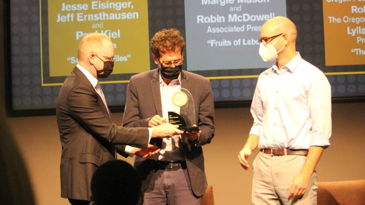 Journalists receiving award for investigative reporting on stage