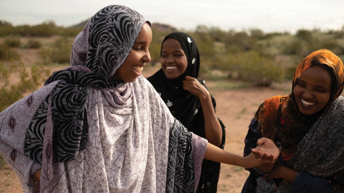 Three women in headscarves laugh together at Papago Park