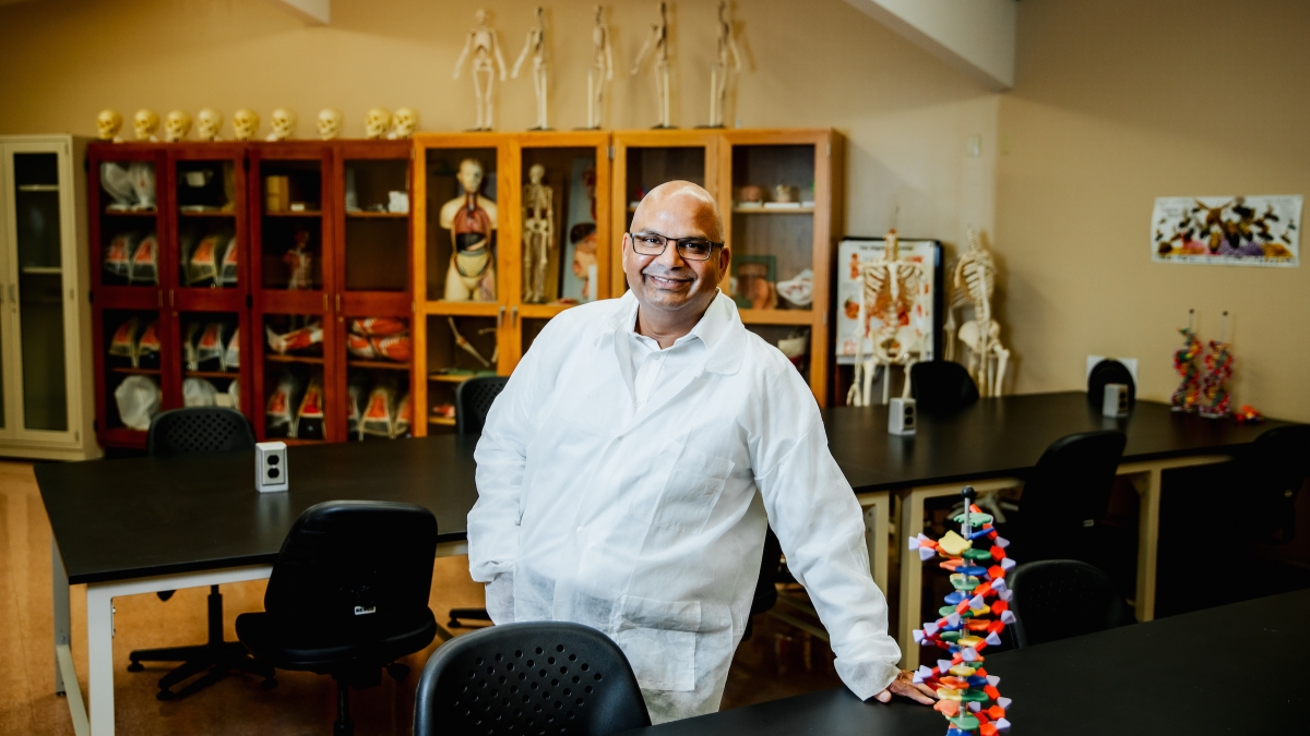 ASU Assistant Teaching Professor Naseem Akhter in a white lab coat in a classroom with skeletons and 3D DNA replicas.