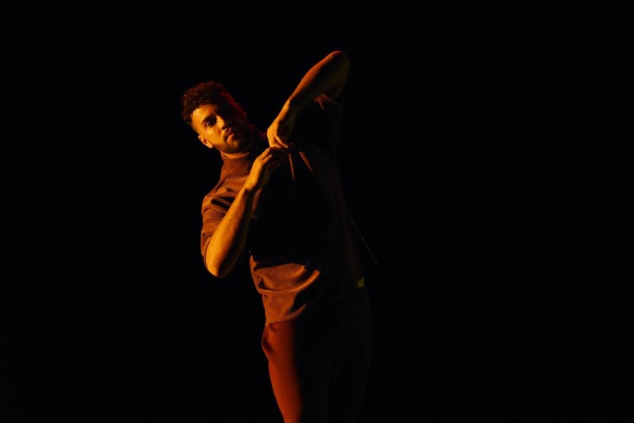 A dancer performs on a dark stage
