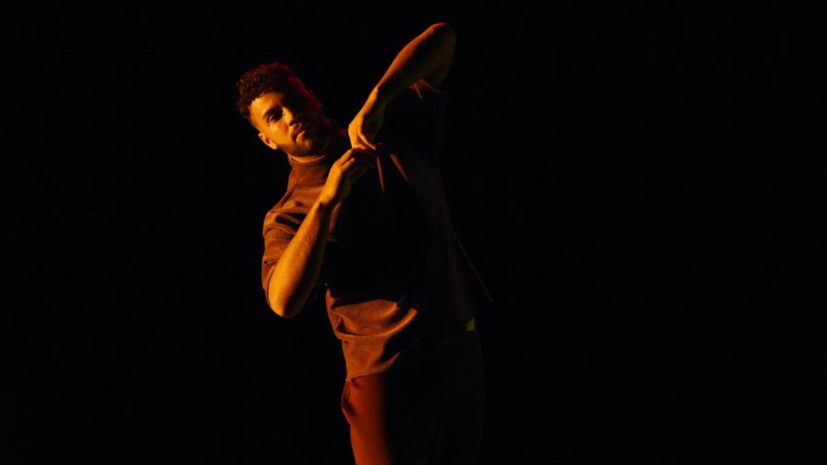 A dancer performs on a dark stage