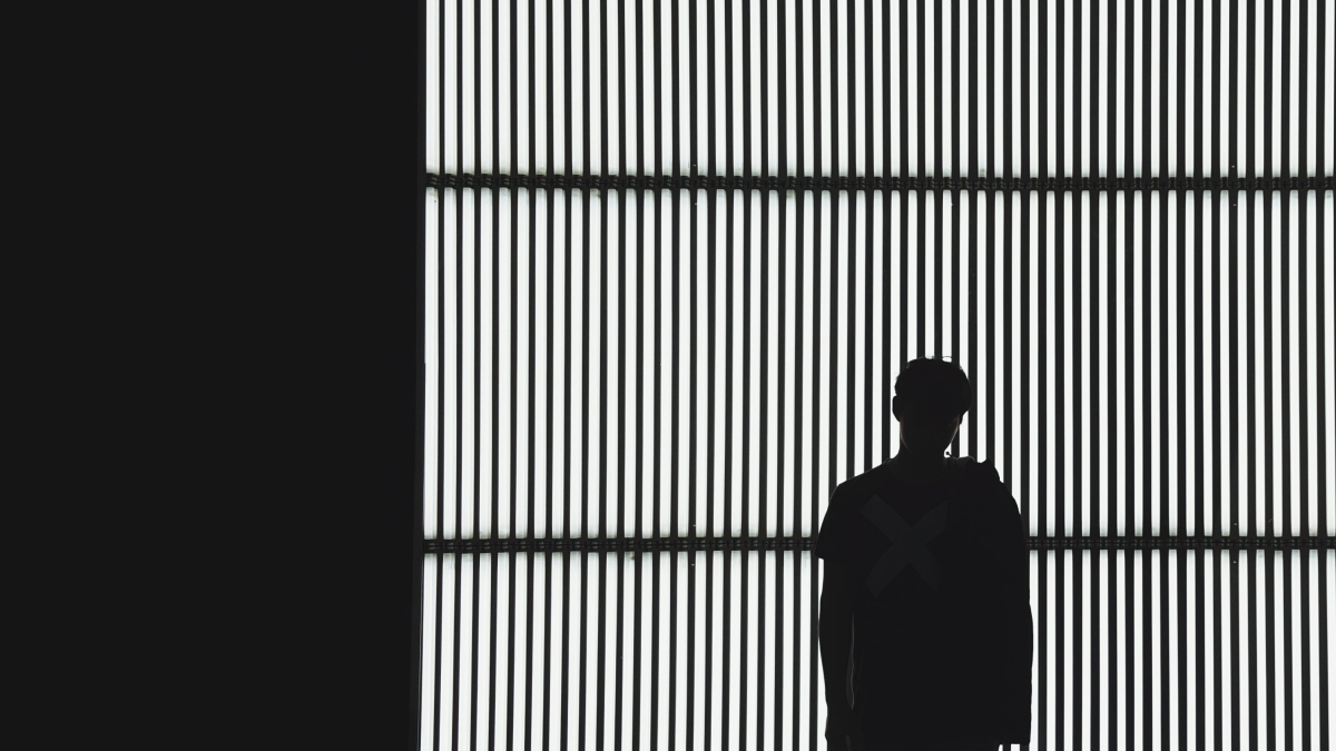 Stock photo of a person's silhouette against a backdrop of iron bars.